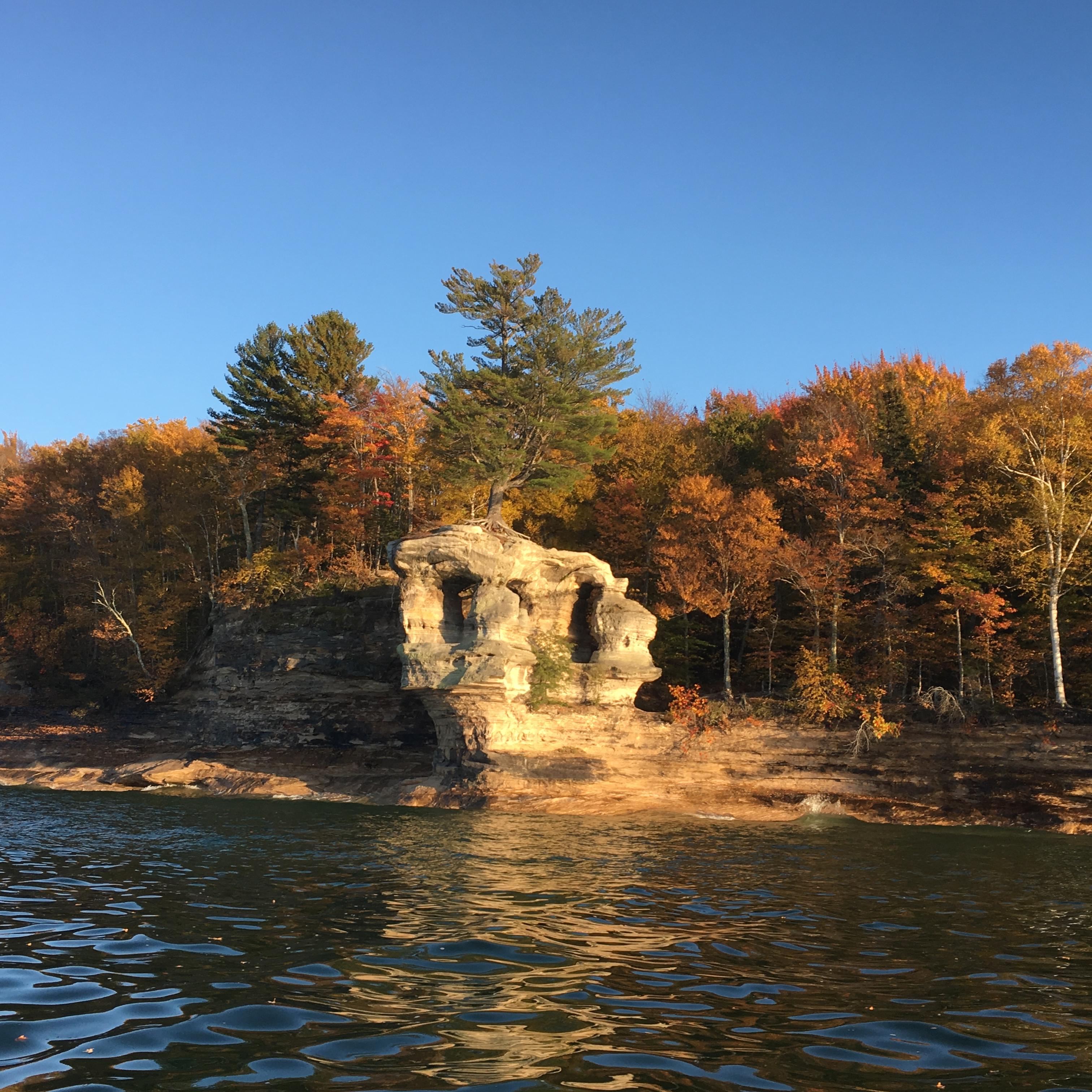 Chapel Rock with green pines and birch trees with yellow and orange leaves.