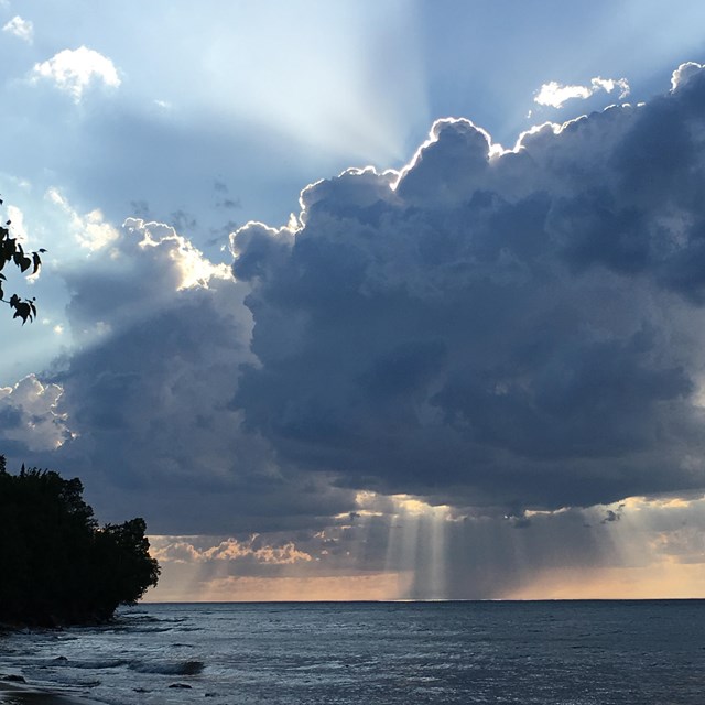 Clouds, sunset, and shafts of rain coming down in distant Lake Superior.