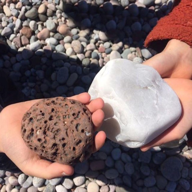 Kids showing off two rocks. One rock is rough the other is smooth.