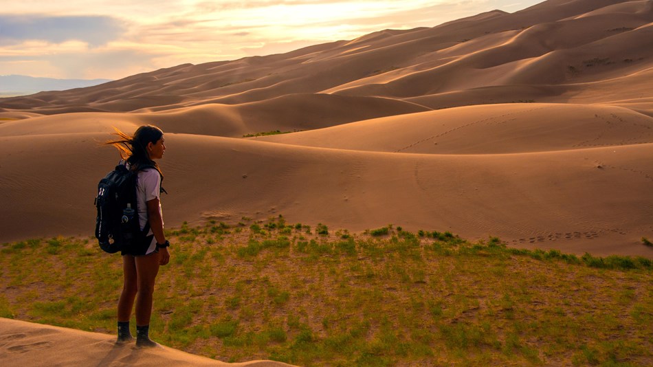 Kid standing near sand dunes at sunset