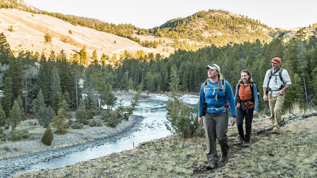 Three hikers along a mountain creek