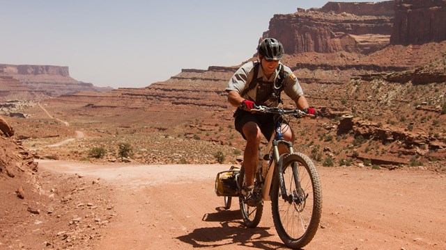 Park ranger on a mountain bike in a desert landscape