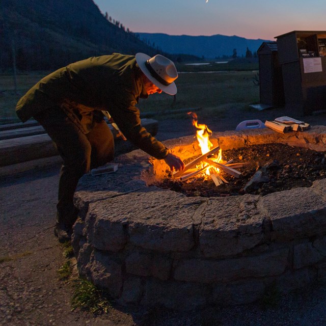 Ranger tending a campfire 