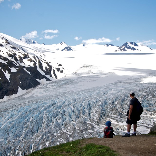 Hikers overlooking large mountain glacier