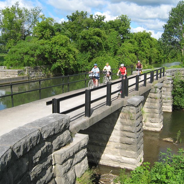 People bicycling over canal