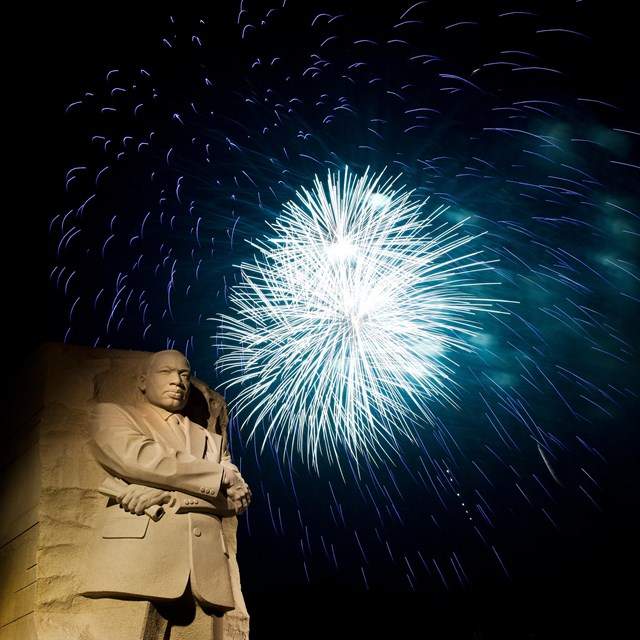 Blue firework explodes over MLK Jr Memorial statue