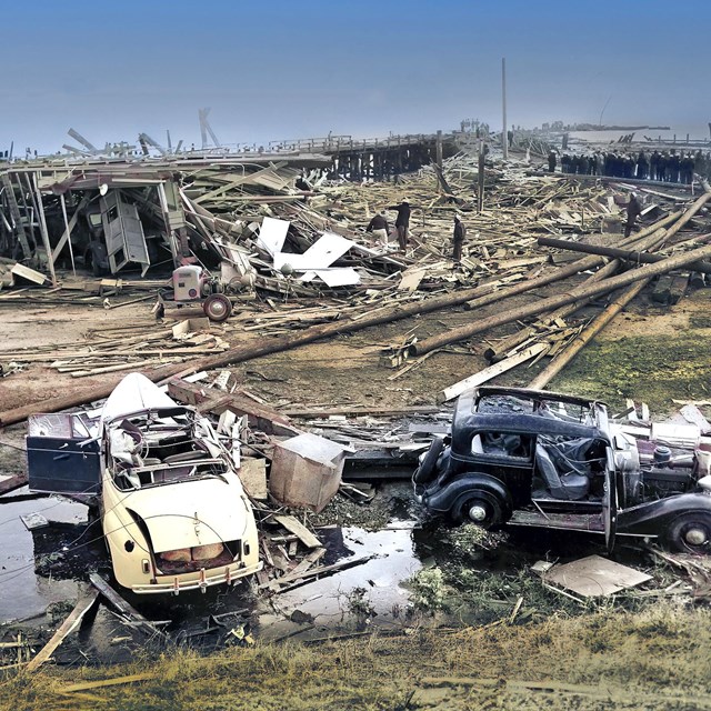 A colorized historic photo of the disaster aftermath which shows a lot of wooden debris and vehicles
