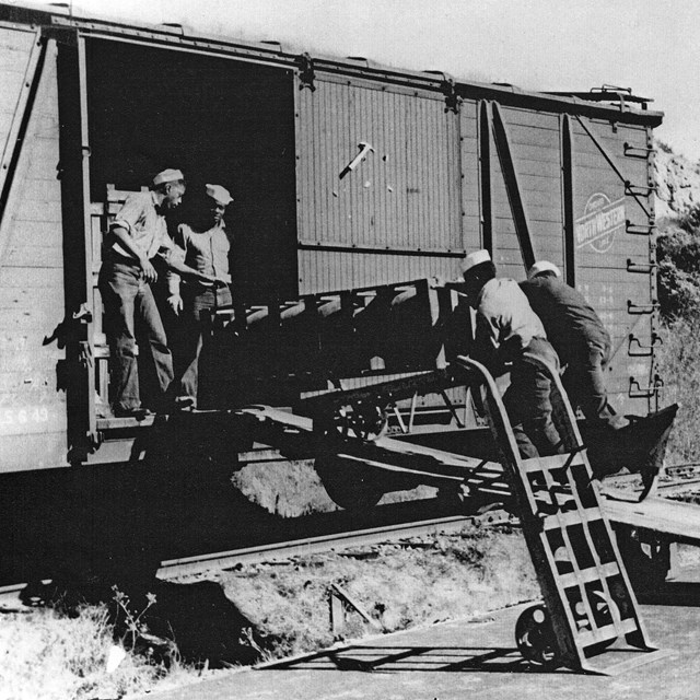 Four African American sailors load munitions into a boxcar.