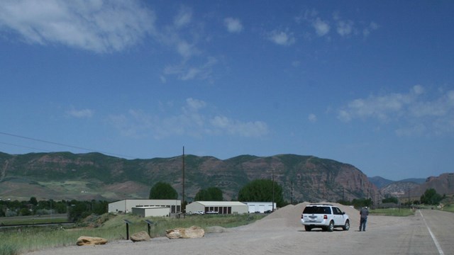 A vehicle is on the side of the highway, with a person standing next to it.