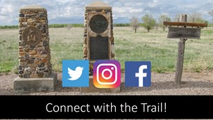 Two stone and one wooden signs stand in front of a vast grass field. "Connect with the trail"