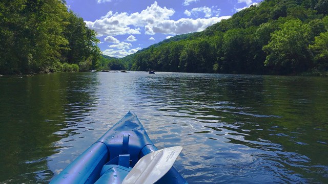 A kayak floats down a sun-drenched river. 