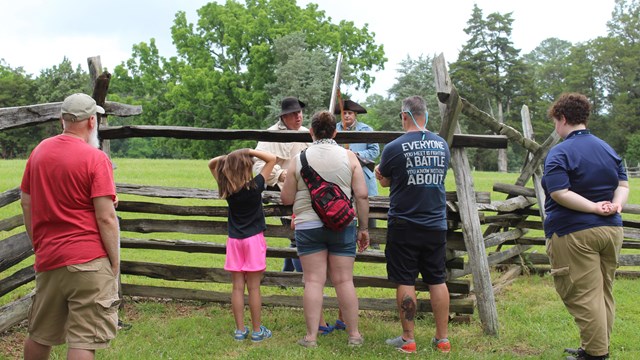 Visitors behind a fence watching a living history black powder demonstration