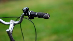 a close up view of a bicycle handlebar with  wooded landscape in the background