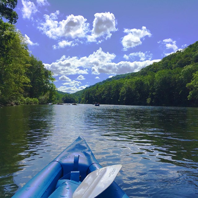 A kayak floats down a sun-drenched river. 