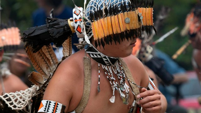 A young person wearing a variety of traditional beads and shells. 