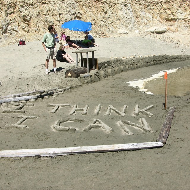 A sand sculpture of a small steam locomotive pulling a number of rail cars.