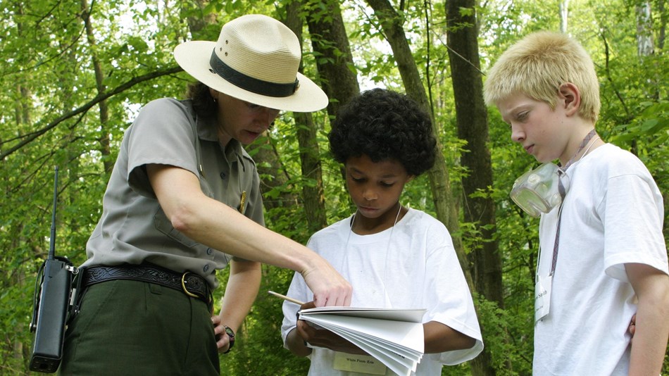 Park ranger explaining directions of study to two children.