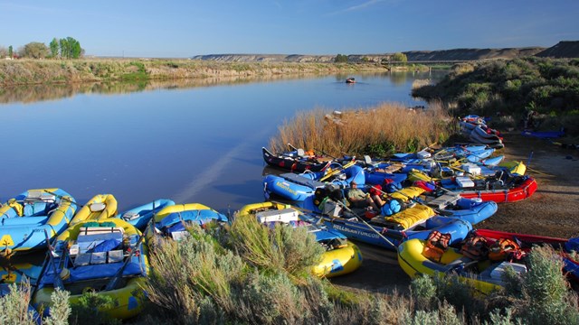 multi-colored rafts grouped together along a river.