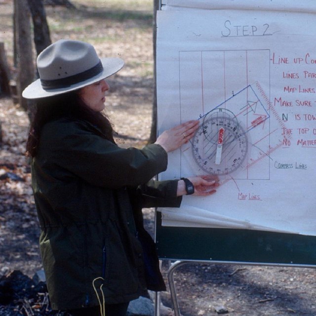 Ranger holding up a large compass teaching orienteering 