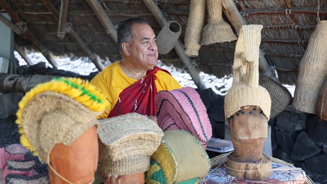 Cultural demonstrator sits in a traditional Hawaiian halau