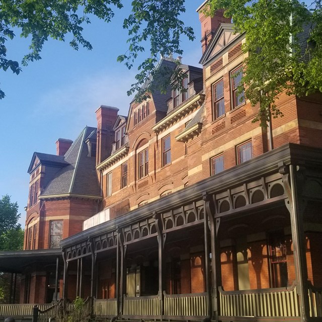 Front porch of Hotel Florence surrounded by blues skies and green trees. 