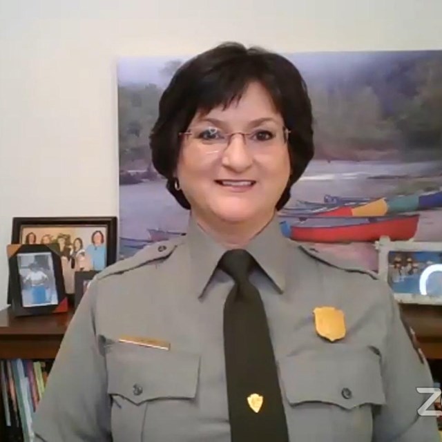A screenshot of a Zoom screen. A ranger sits in an office smiling at the camera.