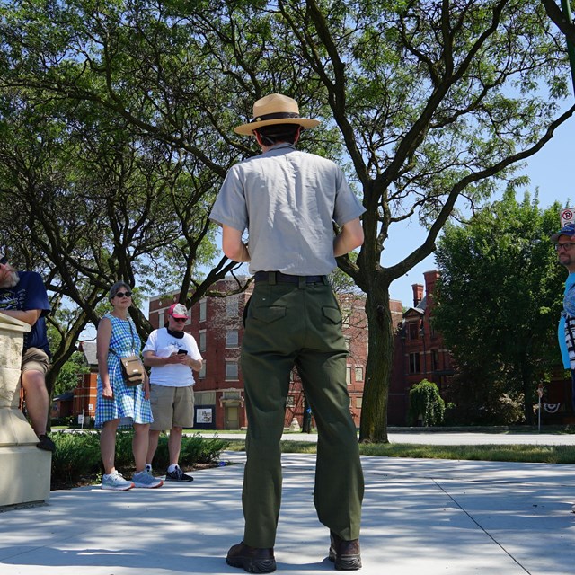 A ranger gives a tour with a group of visitors in front of Hotel Florence. 