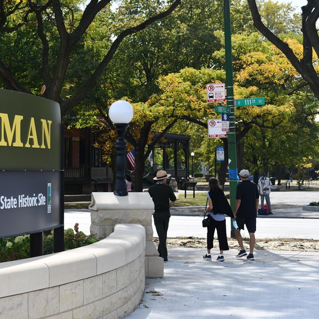 A ranger leads a pair of visitors past the Pullman site sign. 