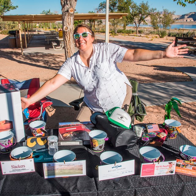 Employee presents table of items for sale at outdoor event