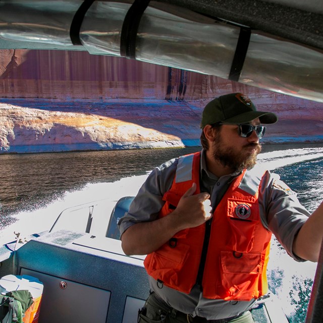 Ranger wearing life jacket while cruising through canyon on motor boat