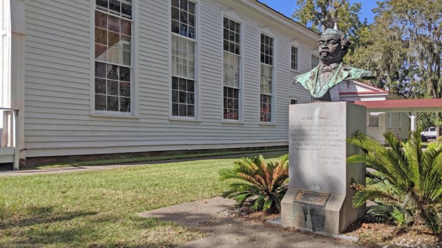 Sculpture of Robert Smalls next to a white church
