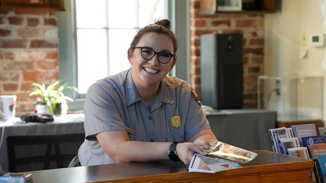 A ranger hands brochures over a front desk.