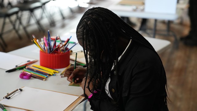 A girl works on a craft at a table.