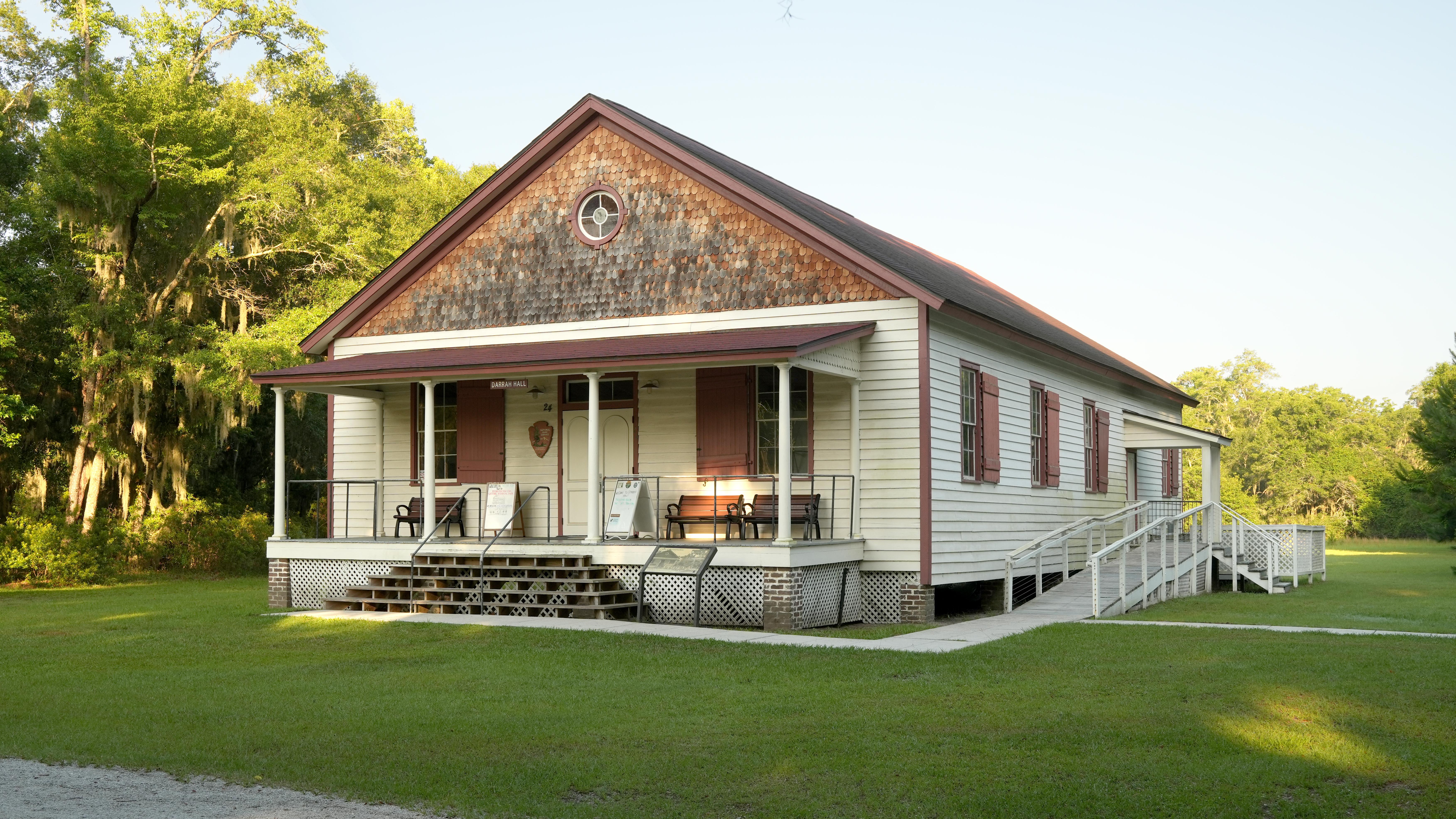Single story white building with red trim and a large porch.