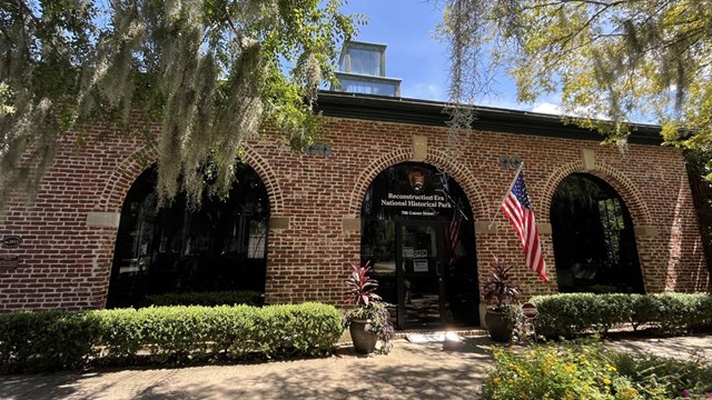 Brick building with arched windows has "Reconstruction Era National Historical Park" above the door.