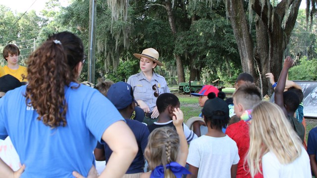 A ranger talking to students outside.
