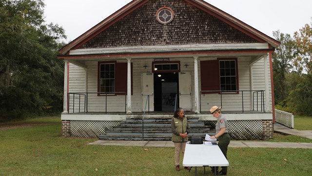 a ranger and volunteer in front of historic building
