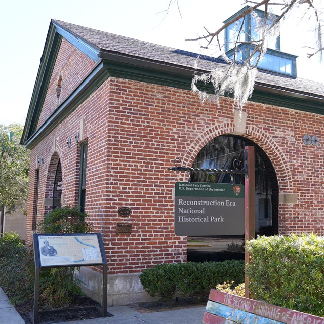 A brick single story building with large arched windows.