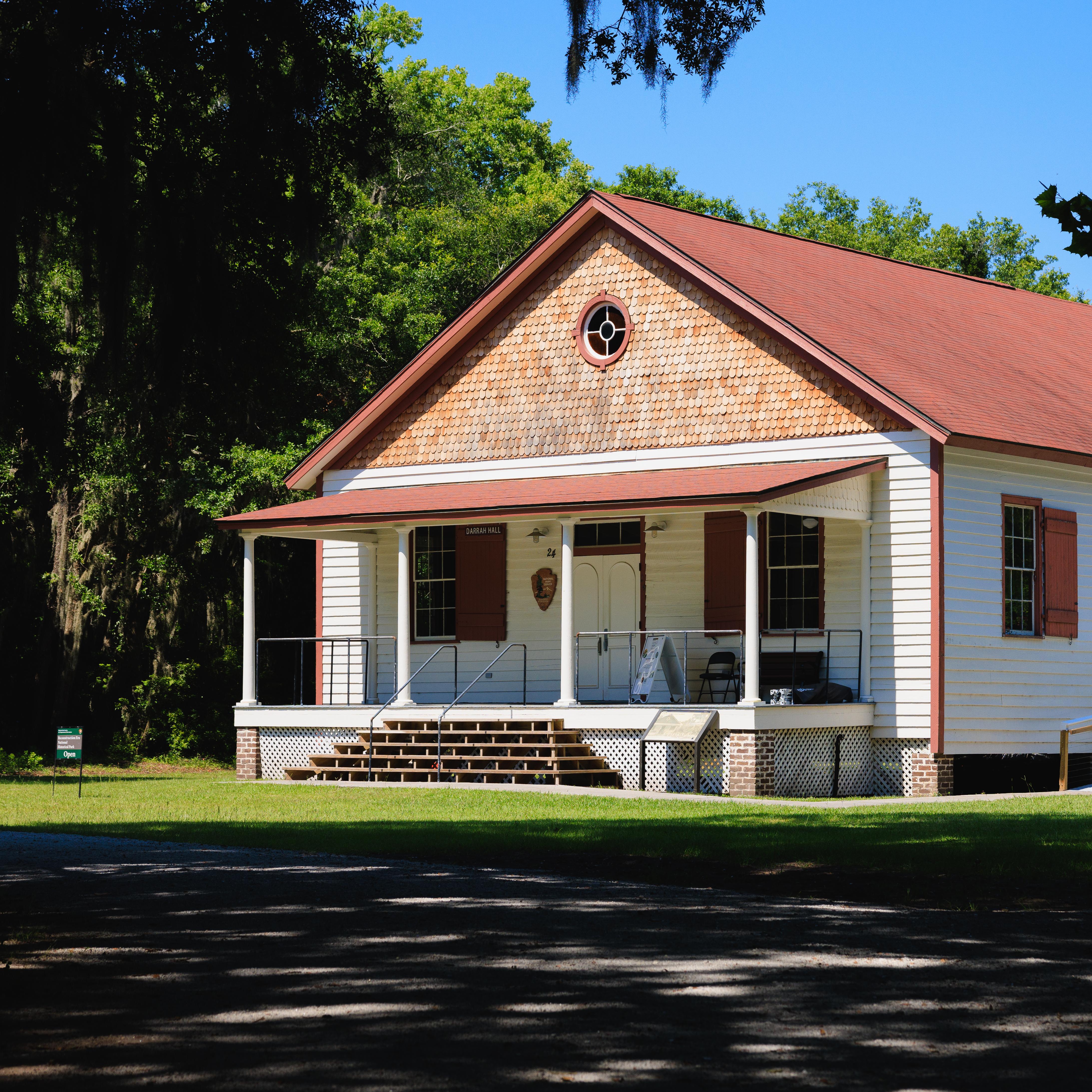 A single-story historic building with a red roof and porch.