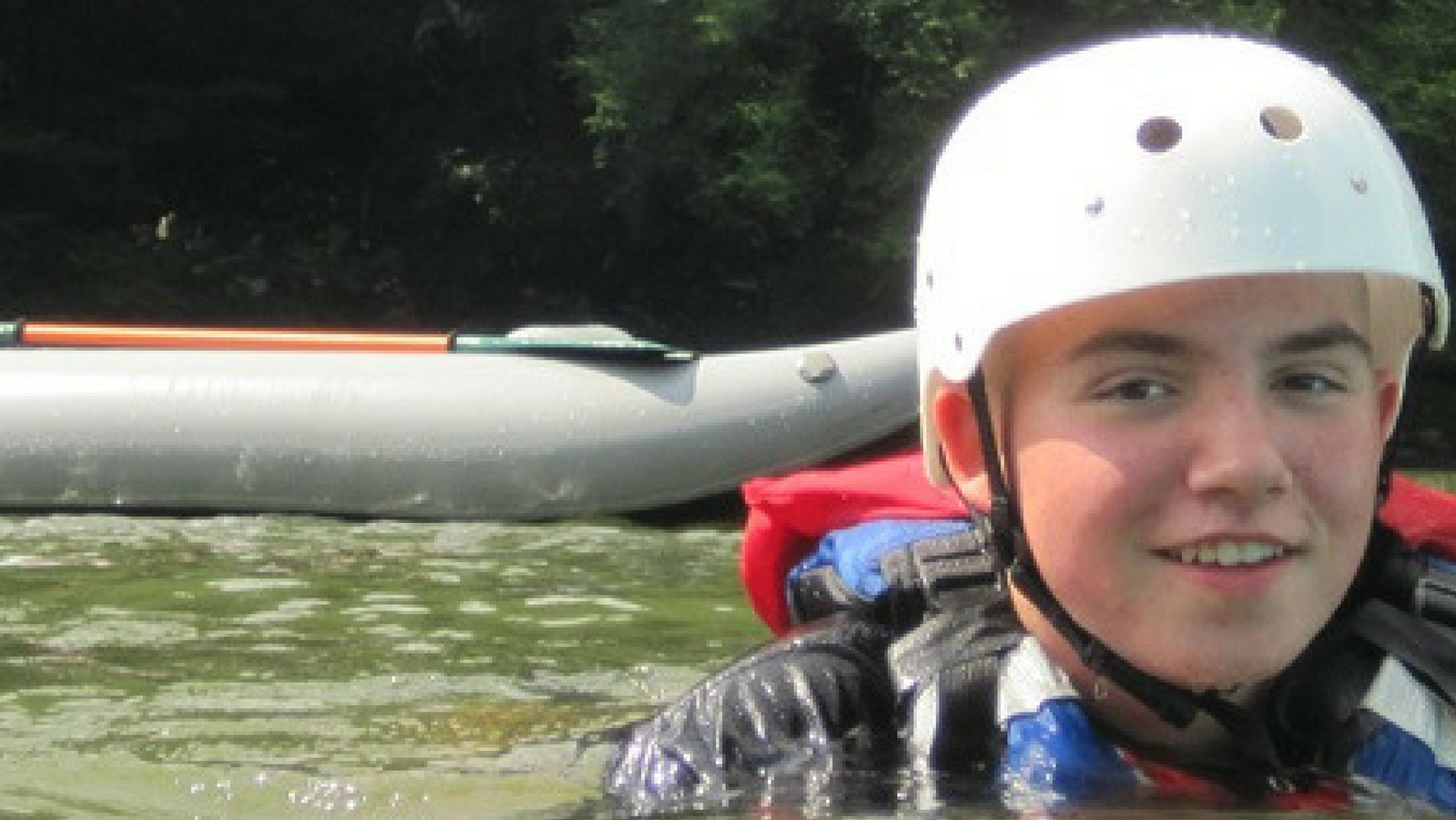 A boy wearing safety gear in a river.