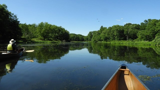 two canoes float on a calm river