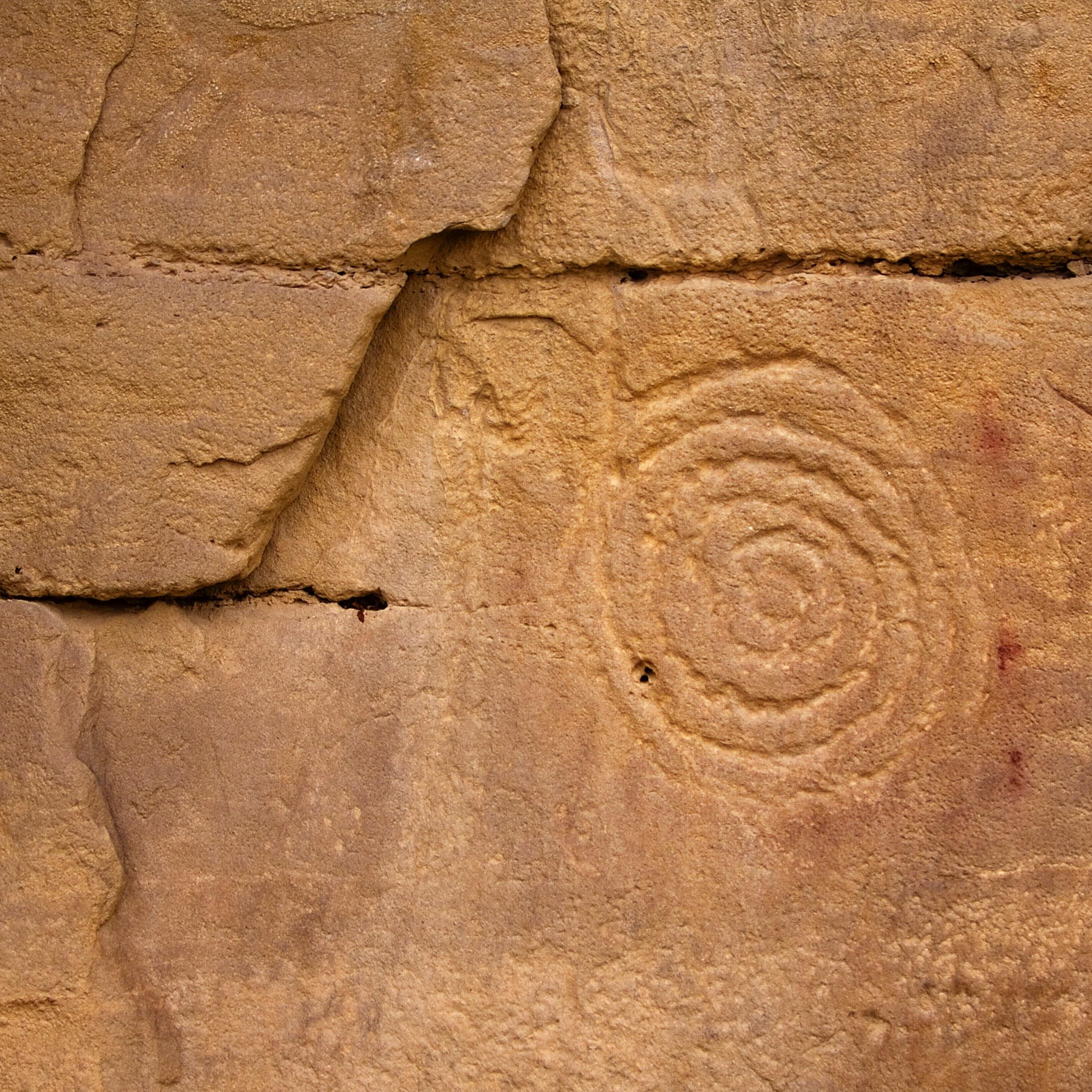 circular petrogrlyph on reddish brown rockface