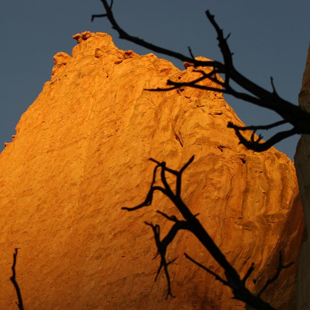 a rock bluff glows in the sunset