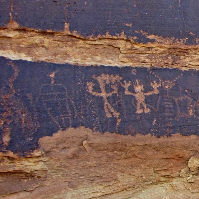 petroglyphs carved into dark red and brown rock
