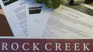 lesson plans fanned out over a poster of "Rock Cree Park" with a stuffed turtle looking on.