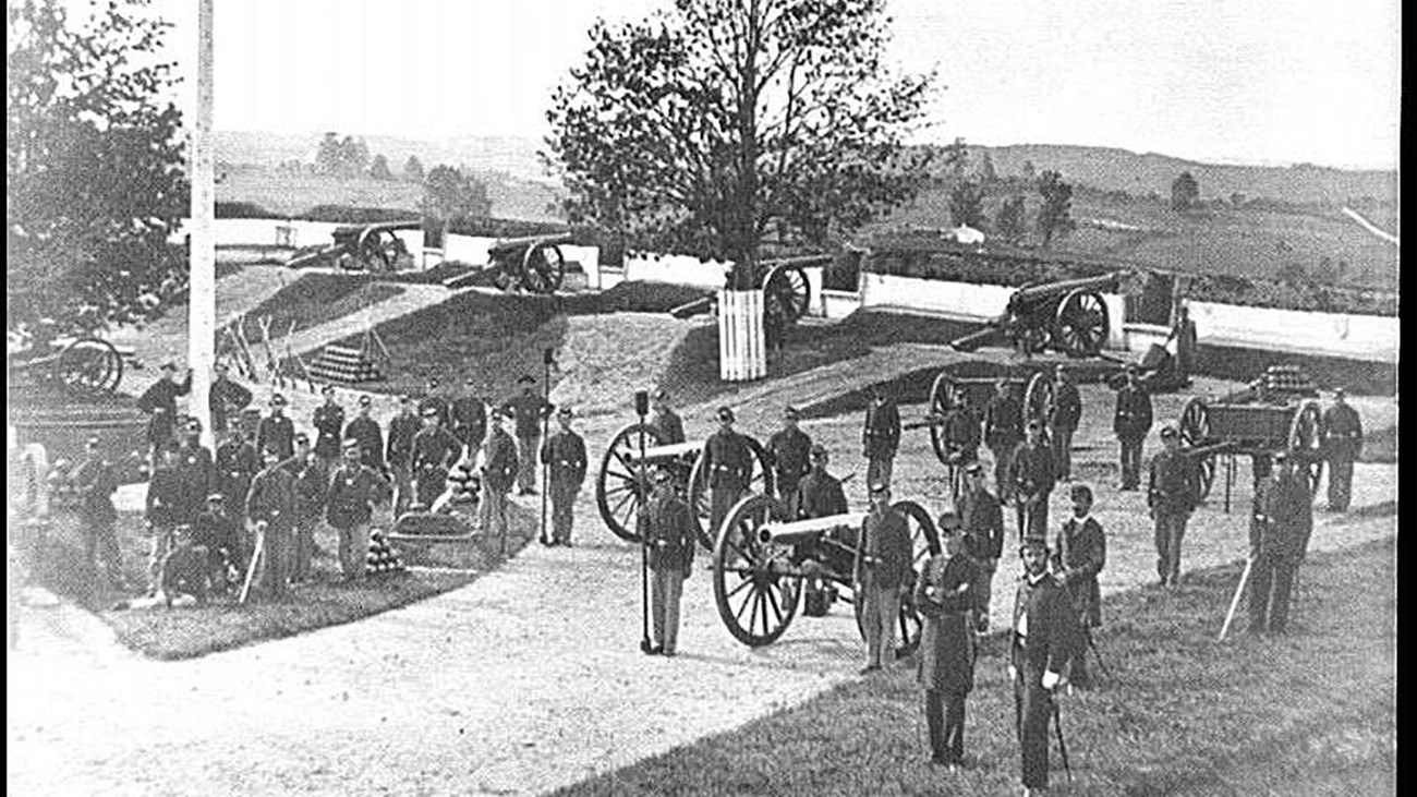 A black and white photo of Civil War era soldiers standing near cannon