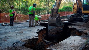 Beach Drive under construction. A large excavator digs into the ground.