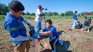 Two middle-school students plant native grasses in Military Field during National Public Lands Day. 