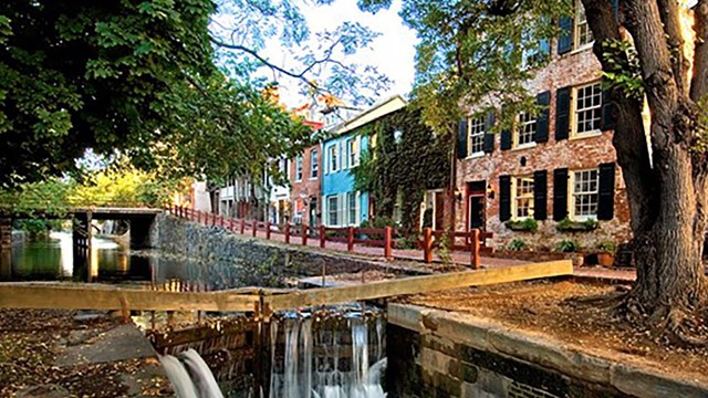 water spills through a canal lock, the canal is lined with colorful houses