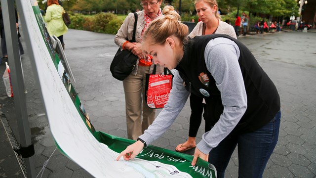 A young volunteer at Rock Creek Park shows visitors where they are on a map.